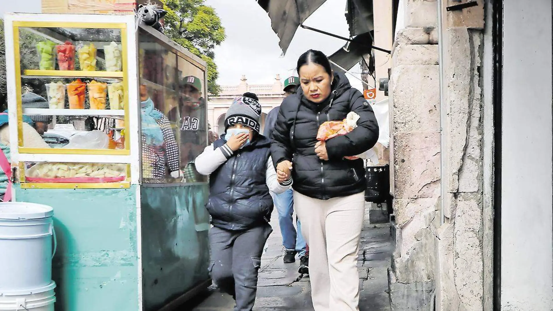 Mujer y niño en el centro de Zacatecas cubiertos con ropa abrigadora